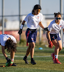 three female athletes playing flag football on a field