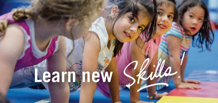 children line up doing a plank in gymnastics class with caption Learn New Skills