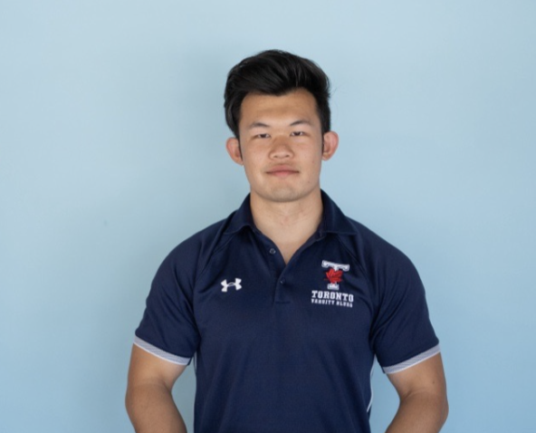 Picture of Alfred Wang against a light blue background, smiling softly and wearing a U of T Varsity Blues t-shirt