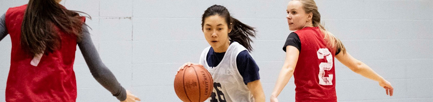 Women playing basketball while dribbling the ball