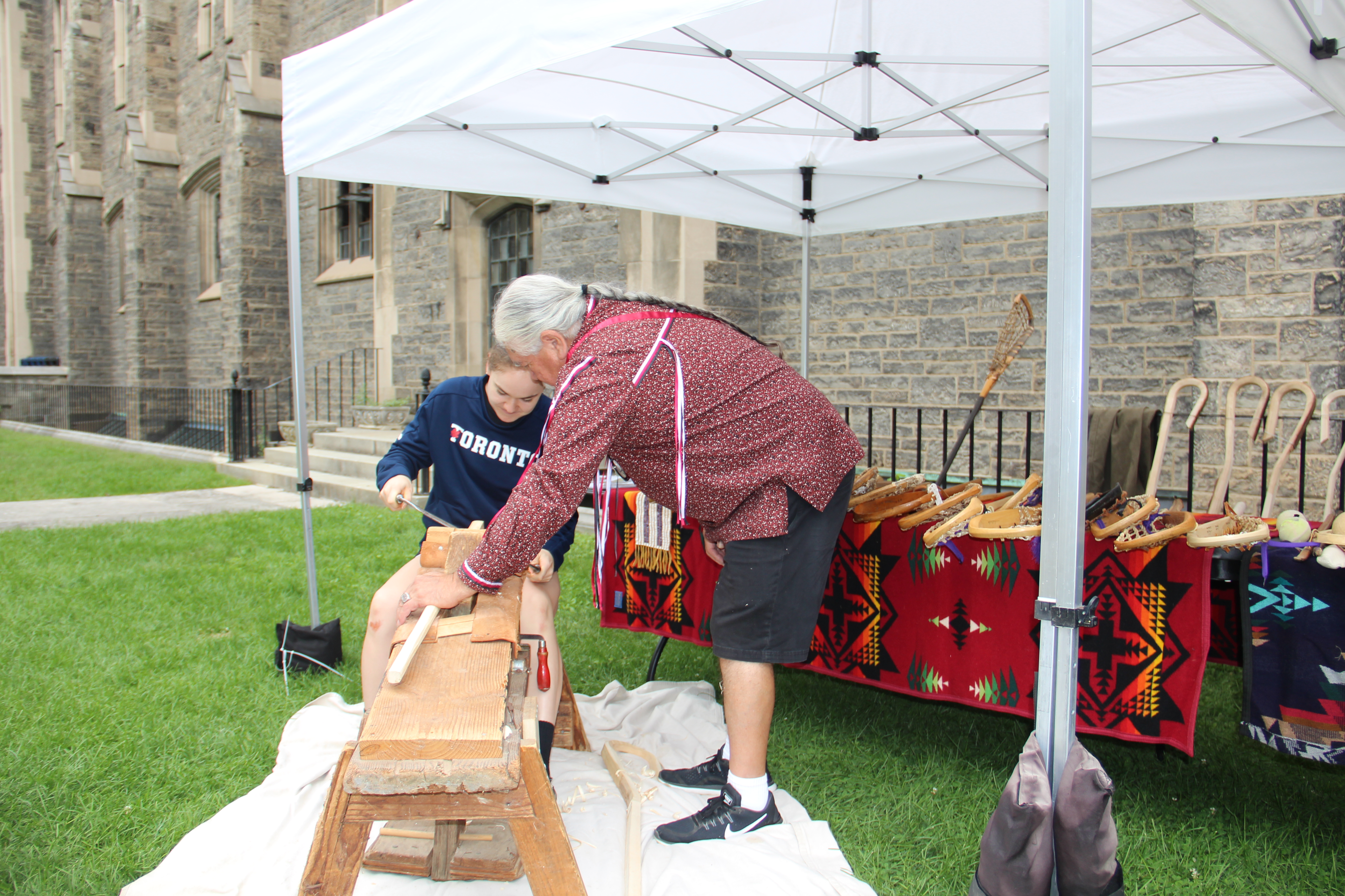 VB lacrosse player Caitlin Downs gets a lesson from Alf Jacques in the art of carving wooden lacross sticks