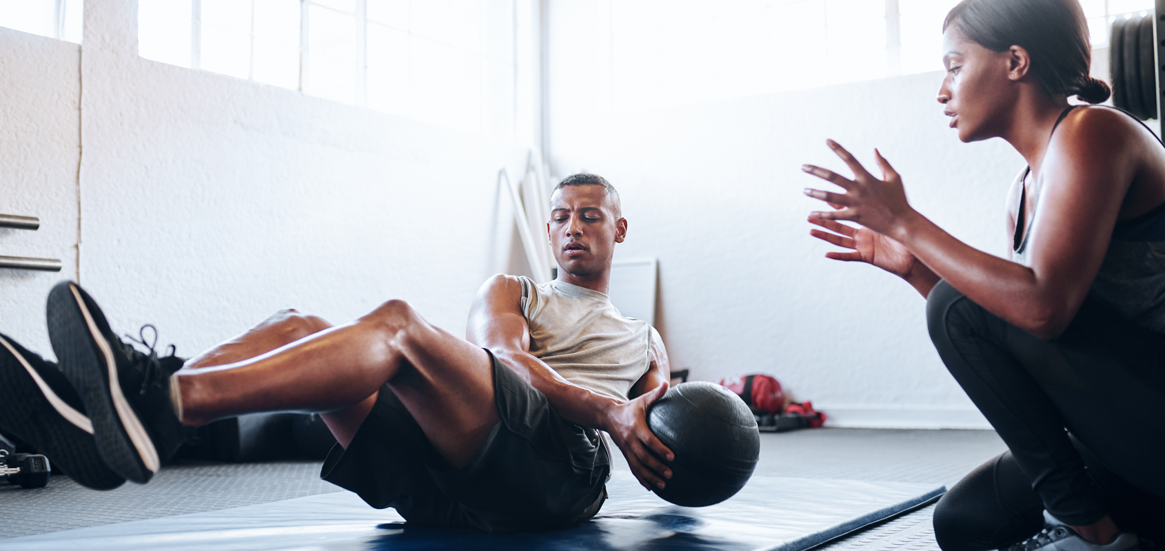 female trainer coaches man through physical activity with medicine ball