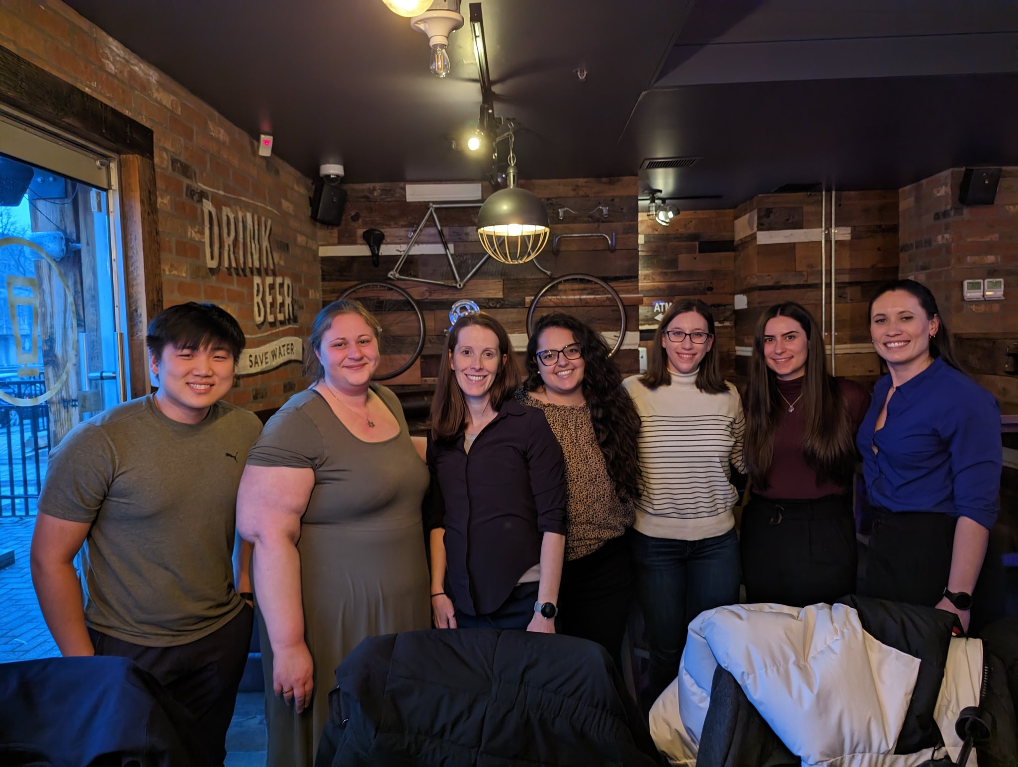 Members of Amy Kirkham's lab, with Kirkham in the middle wearing a black shirt and Elia Rishis to the right of her in a striped beige sweater