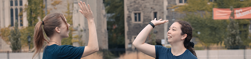 Women high-fiving at the Back-Campus fields