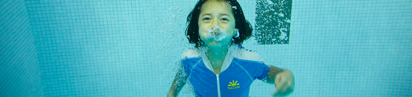 Boy swimming in the water while blowing bubbles